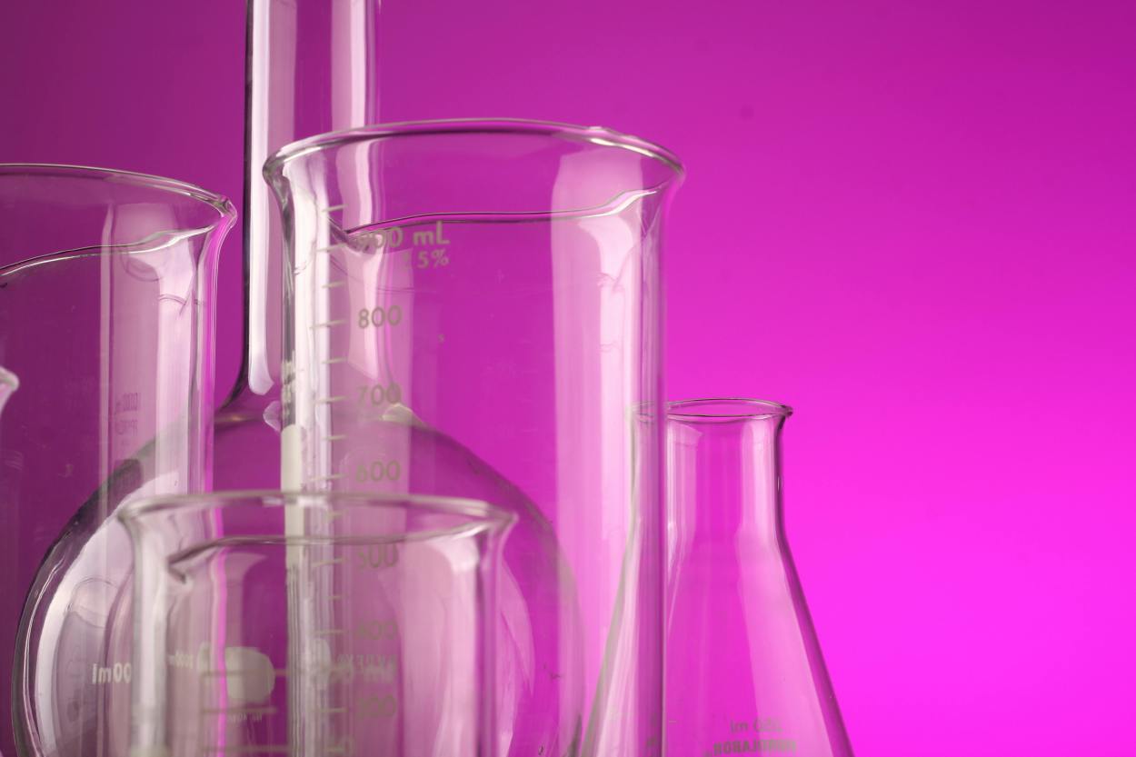A set of scientific glassware on a pink background